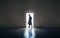 Man silhouette standing in the light of opening door in dark room