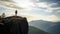 Man silhouette stay on sharp rock peak. Satisfy hiker enjoy view. Tall man on rocky cliff watching down to landscape. Generative