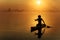 Man in silhouette using paddle for floating on sup board