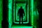 Man in silhouette walking through the creepy hallway with a bright light beaming from the rooms, green toned version