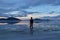 Man sillhoutte walking into sunset of lake Bonneville Salt Flats, Wendover, Western Utah, USA, America. Beautiful summits of