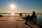 Man sit on bench on wharf construction and looking at sea. Sunny blue sky, smooth level