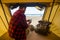 Man sit down inside a tent on wild free camping at the beach using modern connected cellular mobile phone to communicate with