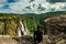 Man siting at hilltop watching the beautiful waterfall at evening