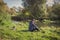 Man sits alone with a cup of coffee on the river bank near the fire.