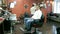 A man sits in an armchair in a barber shop preparing for a haircut