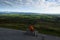 A man sits on a bench near the edge of the road admiring the views at Vee Pass