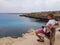 A man sits on a bench on a rock, overlooking the sea. Cyprus, Protaras, May 2018.