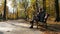 Man sits on a bench and using smartphone. Autumn park.