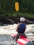 A man sits on a catamaran dressed a life jacket and helmet