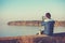 A man sits on the concrete embankment of a lake in evening