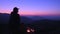 A man sits by a fire in the mountains and looks at the night sky. Campfire in the tent camp at night. Hiking in the mountains