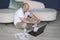 A man sits on the floor, works on laptops, studies reporting documents.