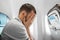 A man sits in front of an airplane window and is nervous, afraid to fly, the cabin of a passenger aircraft. Aerophobia, fobilya,