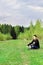 Man sits on grass on edge of forest