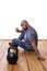 A man sits with a hamburger on the floor and looks at a weight