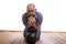 A man sits with a hamburger and a weight on the wooden floor.