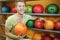 Man sits near shelves with balls in bowling club