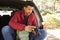 Man sits in the open back of car in forest checking camera