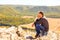 A man sits on a rock on the High Mountain and looks out into the distance on the Ural Mountains