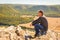 A man sits on a rock on the High Mountain and looks out into the distance on the Ural Mountains,