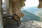 Man sits on stone steps in cave with huge hole in the wall in Crimea