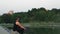 Man Sits on Stones on Lake Shore and Repeats Mantra Holding Pouch with Rosary in Hand