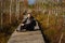 A man sits on a wooden path in a swamp in Yelnya, Belarus