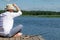 Man sits on a wooden pier for fishing using spinning on the river