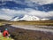 Man sitting alone on the river bank against snowy mountain and b