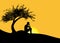 Man sitting alone under a tree on a mountain at sunset