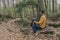 Man sitting with backpack on woods in forest.Stylish hiker outdoor lifestyle.Travel wanderlust concept. Copy space