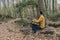 Man sitting with backpack on woods looking horizon in forest.Stylish hiker outdoor lifestyle.Travel wanderlust concept.Copy space