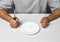 man sitting behind a table with fork and knife in hands and empty plate, Time to eat - therapeutic fasting concept