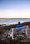 Man sitting on a bench on Marginal Way path along the rocky coast of Maine in Ogunquit during winter