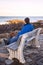 Man sitting on a bench on Marginal Way path along the rocky coast of Maine in Ogunquit during winter