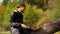 A man sitting on a bench reading a book. Young man works behind a laptop in the autumn forest. He sits on the ground in