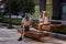 Man is sitting on the bench, watching his smartphone while two little girls are playing next to him