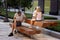 Man is sitting on the bench, watching his smartphone while two little girls are playing next to him