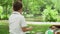 Man sitting on blanket with children in park. Children playing with soap bubbles