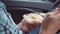 Man, sitting in a car, eats a salad with mayonnaise from plastic disposable dishes