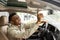 Man sitting in car pushing buttons, opening car sunroof or inspecting car.