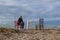 Man Sitting in a Chair Facing the Sea and a Small Table with a Colander resting on it with Wood Remains