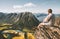 Man sitting on cliff edge relaxing with aerial mountains landscape