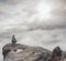 Man sitting on cliff enjoying mountains and clouds landscape