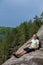 Man sitting on cliff relaxing, above the lake Yastrebinoye, Priozersky district, Leningrad region, Russia