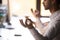 Man sitting at desk holding hands in mudra meditating, closeup