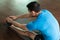 Man sitting down on exercise mat while touching his toes