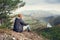 Man sitting on the edge of the cliff above mountaine valley