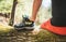 Man sitting on the fallen tree log over the mountain forest stream while he drying his trekking boots. Boots close-up photo.